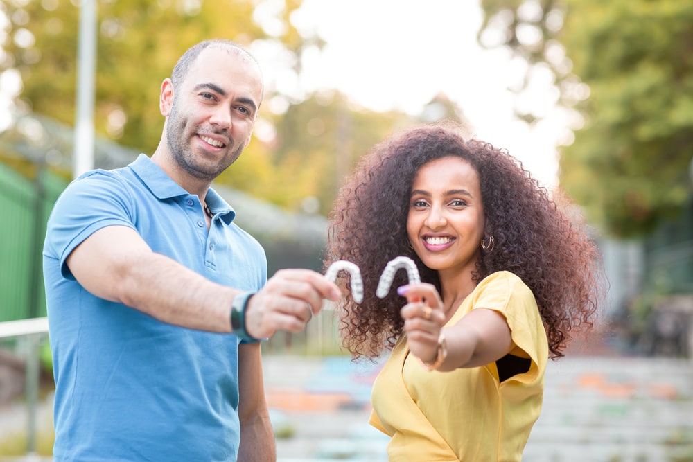 Happy and smiling couple holding an invisaligne